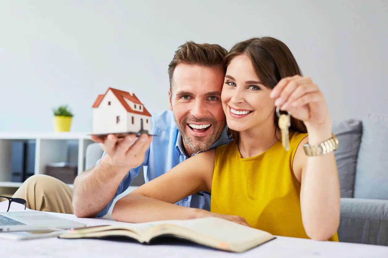 Couple holding house model and keys.