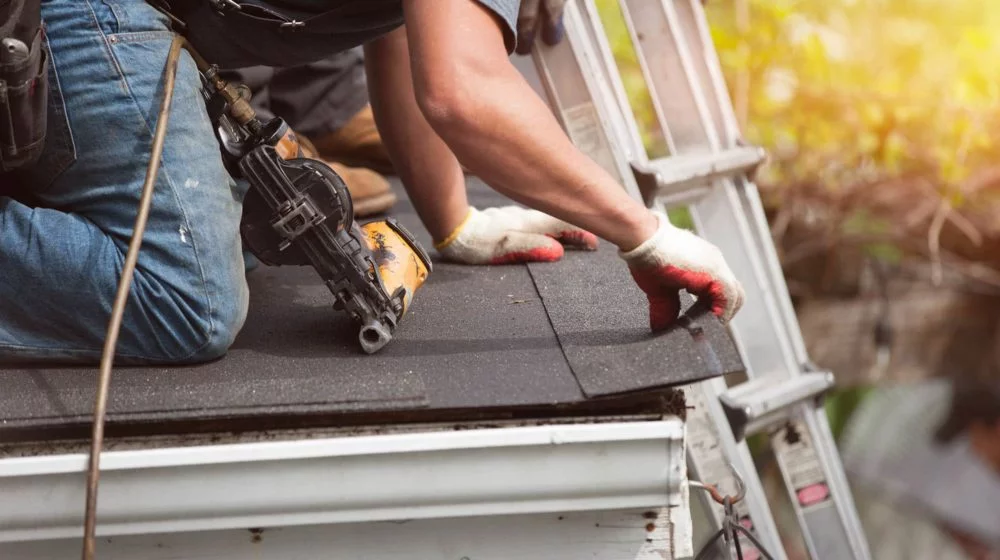 A roofer installing shingles on a roof.