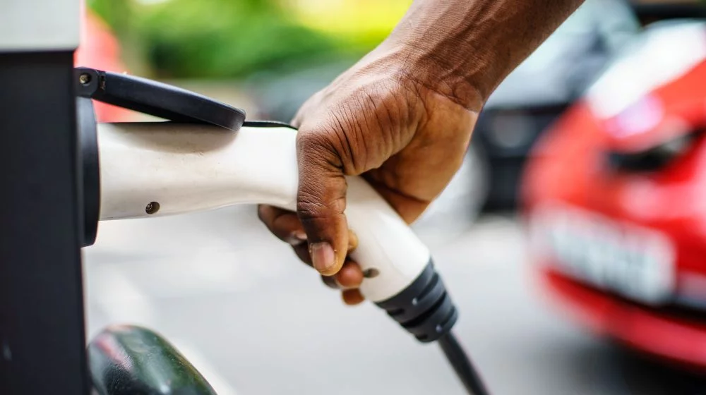 Hand plugging in an electric car charger.